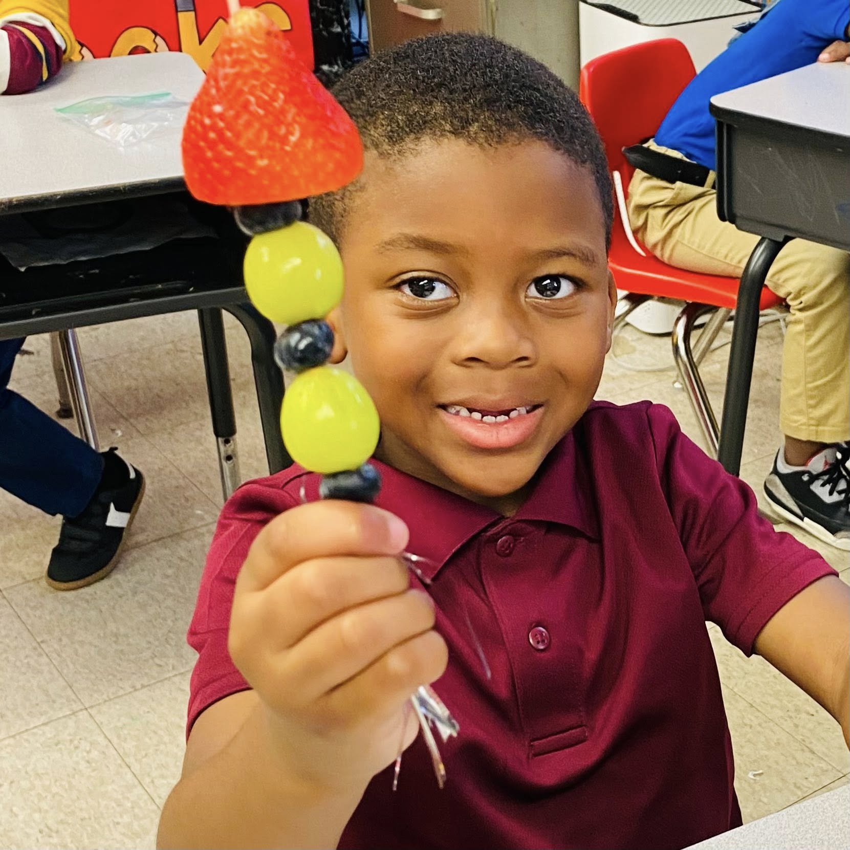 A boy holding a fruit kabob.